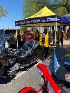 People in yellow vests near motorcycles under a tent that reads 