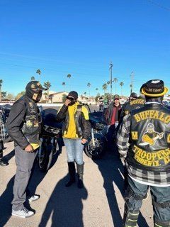 Motorcycle club members standing outdoors, some wearing jackets with 