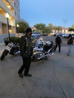 A group of bikers standing near their motorcycles in an outdoor setting.