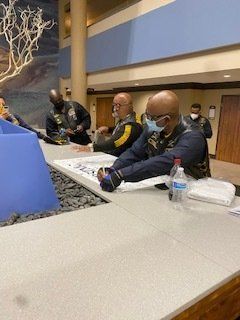 People in uniform at a counter, some wearing masks. Indoor setting.