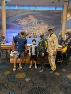 Four people pose near a large mural and reception desk. One child and three adults are present.