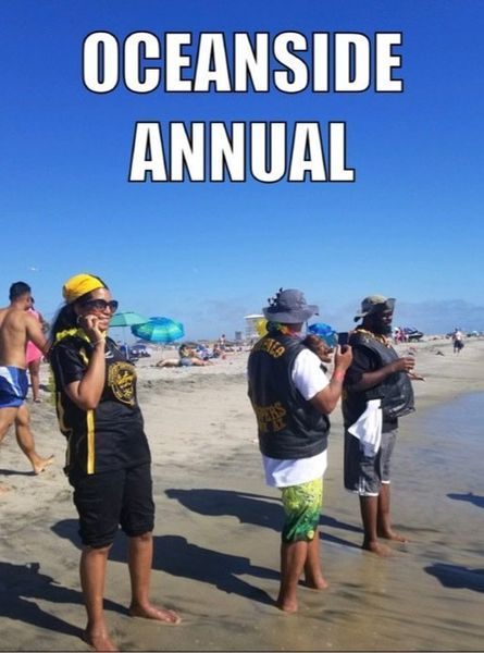 People on a beach in Oceanside, CA. Several wear vests with patches. Others swim and relax. Blue sky, sunny day.