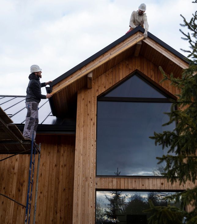 two men are working on the roof of a wooden building