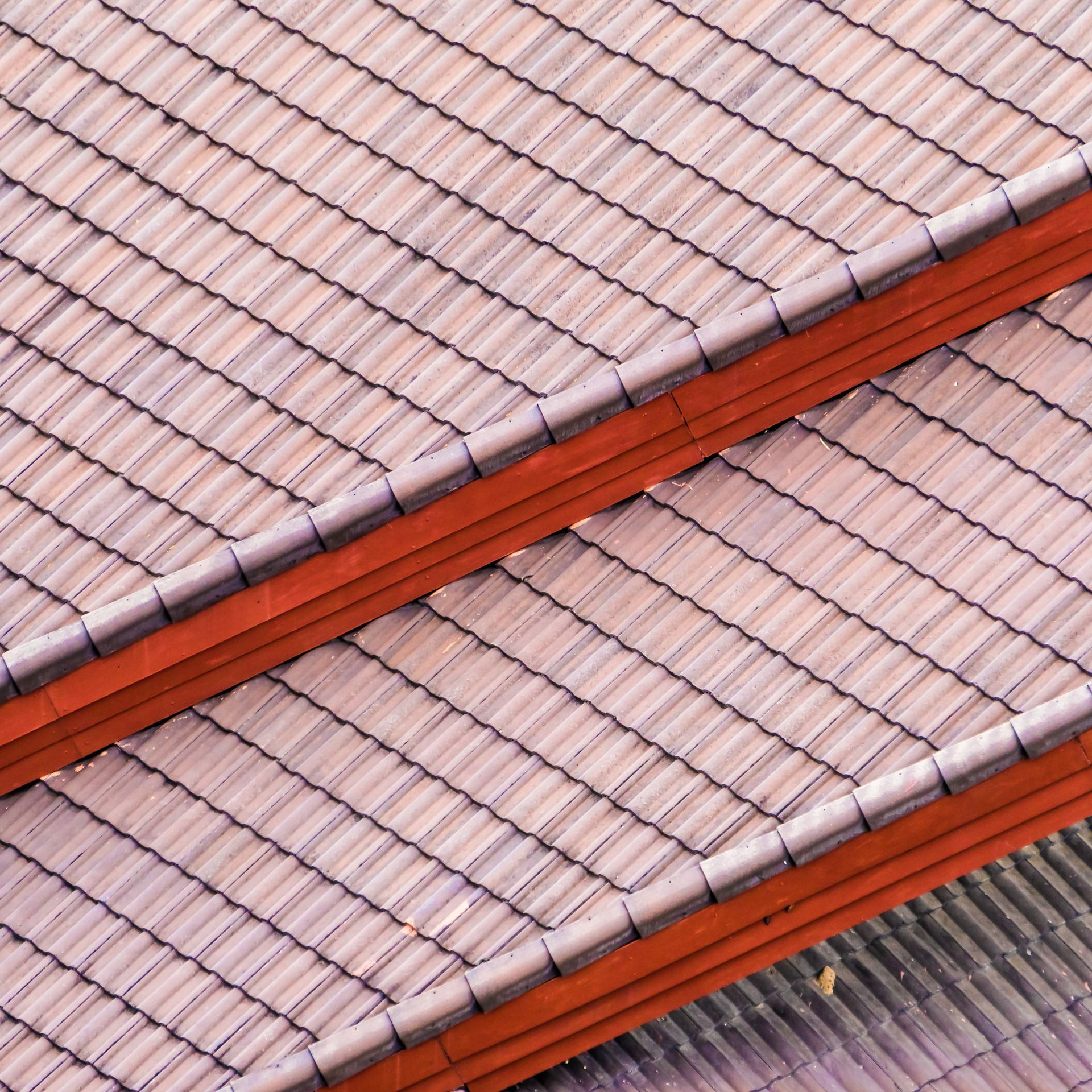 a close up of a tiled roof with a red gutter .