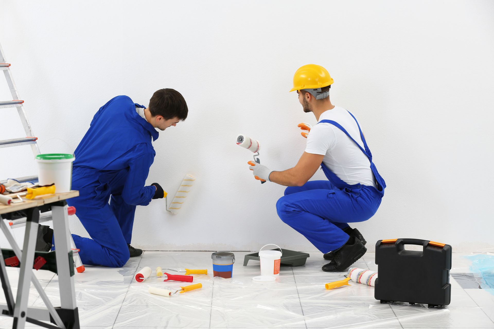 Two men are painting a wall together in a room.