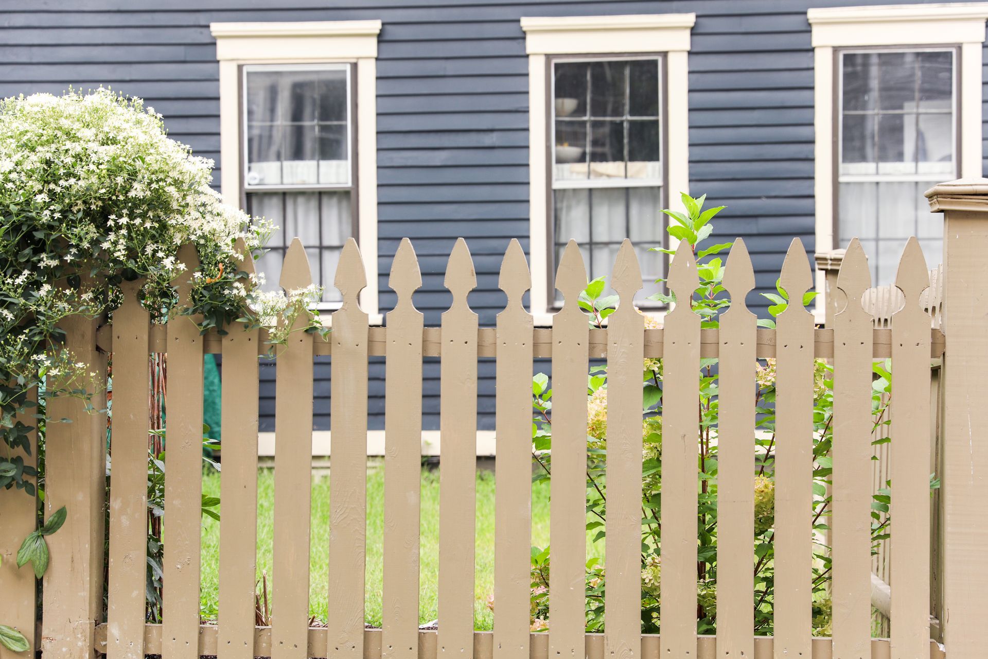 a wooden picket fence is in front of a blue house .