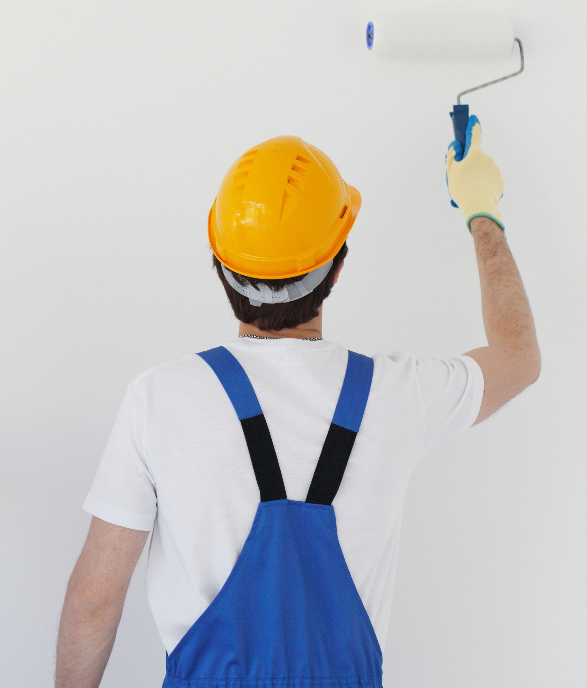 a man wearing a hard hat is painting a wall with a paint roller