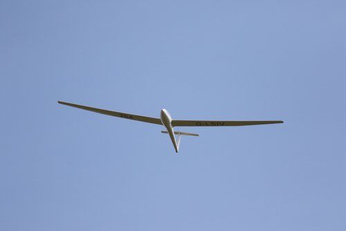 A glider is flying through a clear blue sky.
