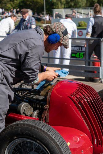 A man is working on the engine of a red race car.