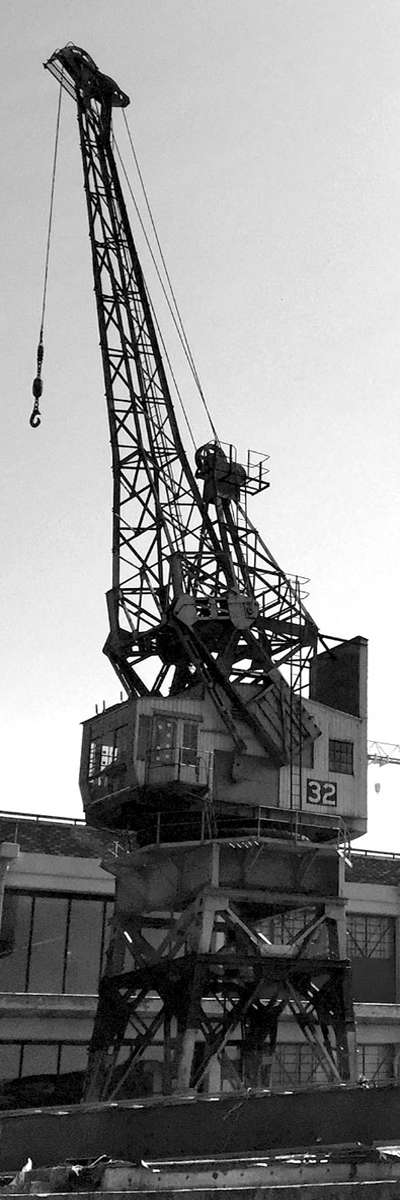 A large crane is sitting on top of a building in a black and white photo.