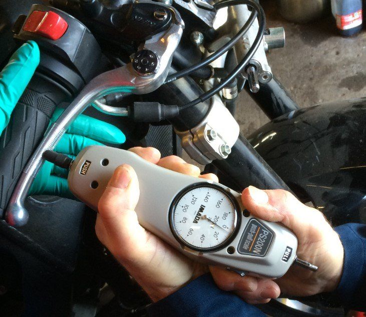 A person is measuring a brake lever on a motorcycle