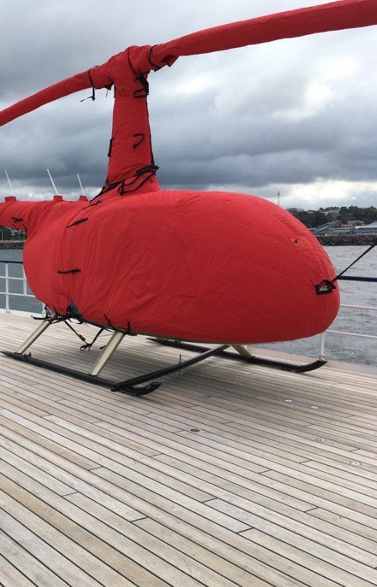 A red helicopter is sitting on a wooden deck.