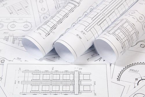 Three rolls of drawings are sitting on top of each other on a table.