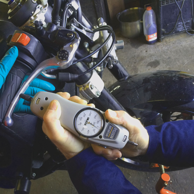 A person is holding a gauge that says ' nm ' on it