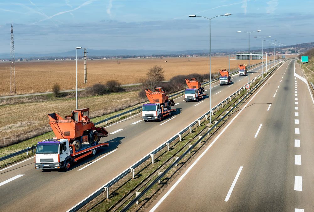 A Row Of Trucks Are Driving Down A Highway — Gympie/Childers Towing Pty Ltd in Childers, QLD