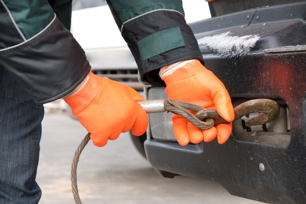 A Person Wearing Orange Gloves Is Towing A Car — Gympie/Childers Towing Pty Ltd in Maryborough, QLD