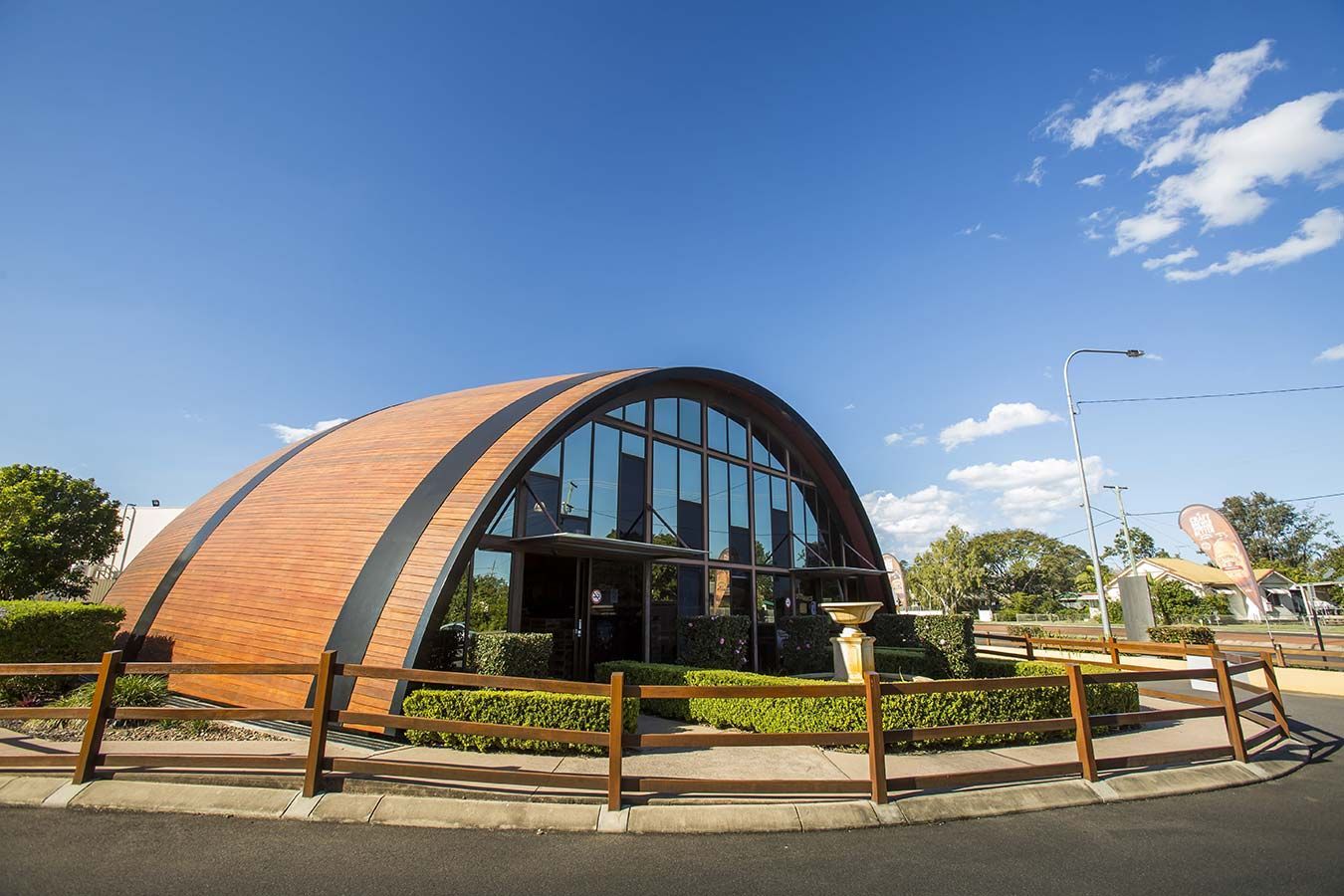 A Large Brick Building With A Wooden Fence Around It — Gympie/Childers Towing Pty Ltd in Bundaberg, QLD
