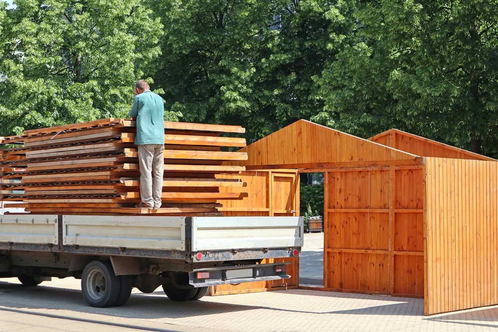 A Man Is Loading Wood Into The Back Of A Truck — Gympie/Childers Towing Pty Ltd in Sunshine Coast, QLD