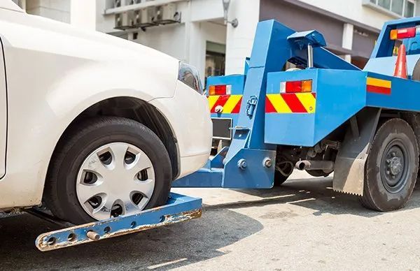 A White Car Is Being Towed By A Blue Tow Truck — Gympie/Childers Towing Pty Ltd in Sunshine Coast, QLD