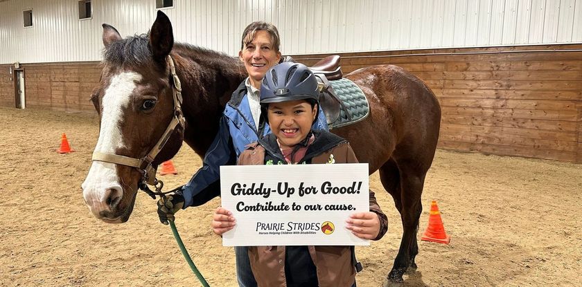 A woman and a child are standing next to a horse holding a sign.