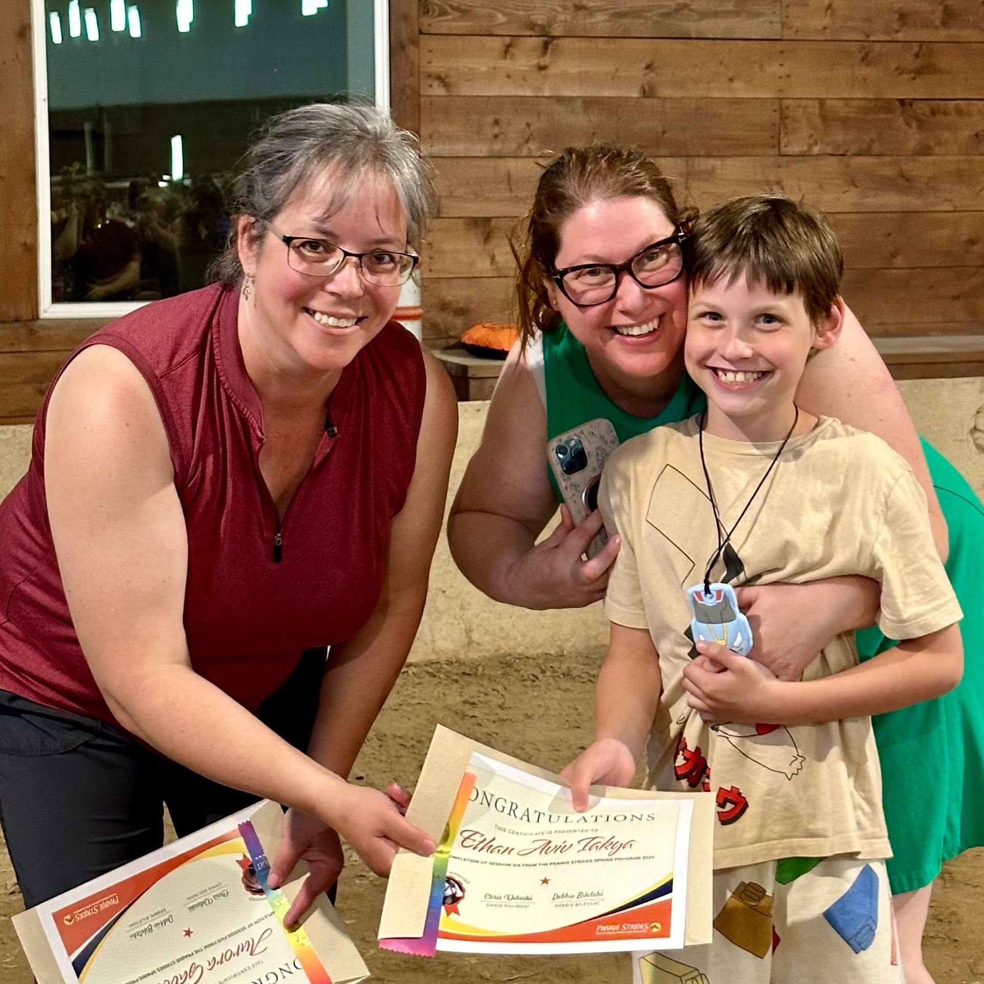 Two women and a boy are posing for a picture holding certificates