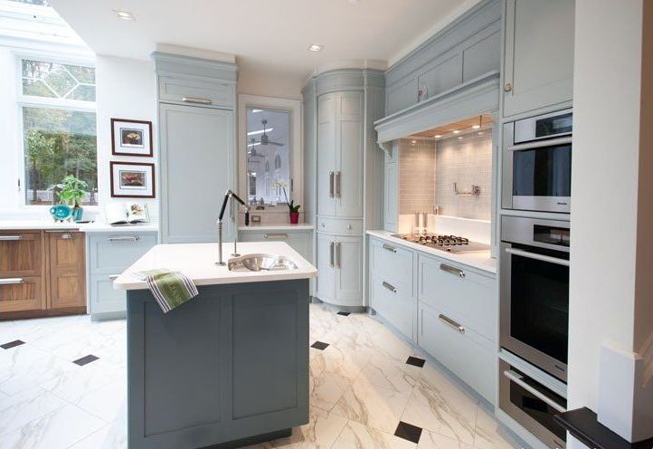 Elegant blue kitchen with marble floor, island, and built-in appliances.