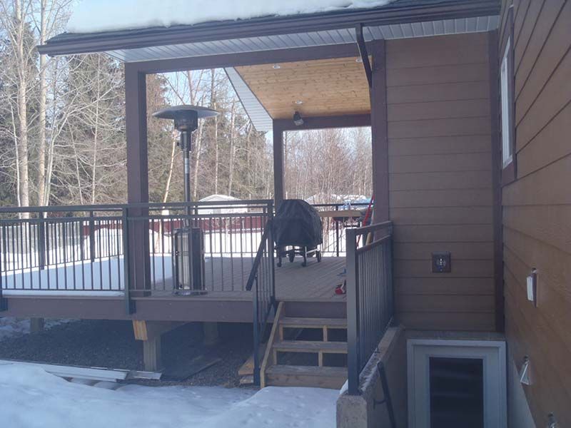 A house with a deck and stairs in the snow