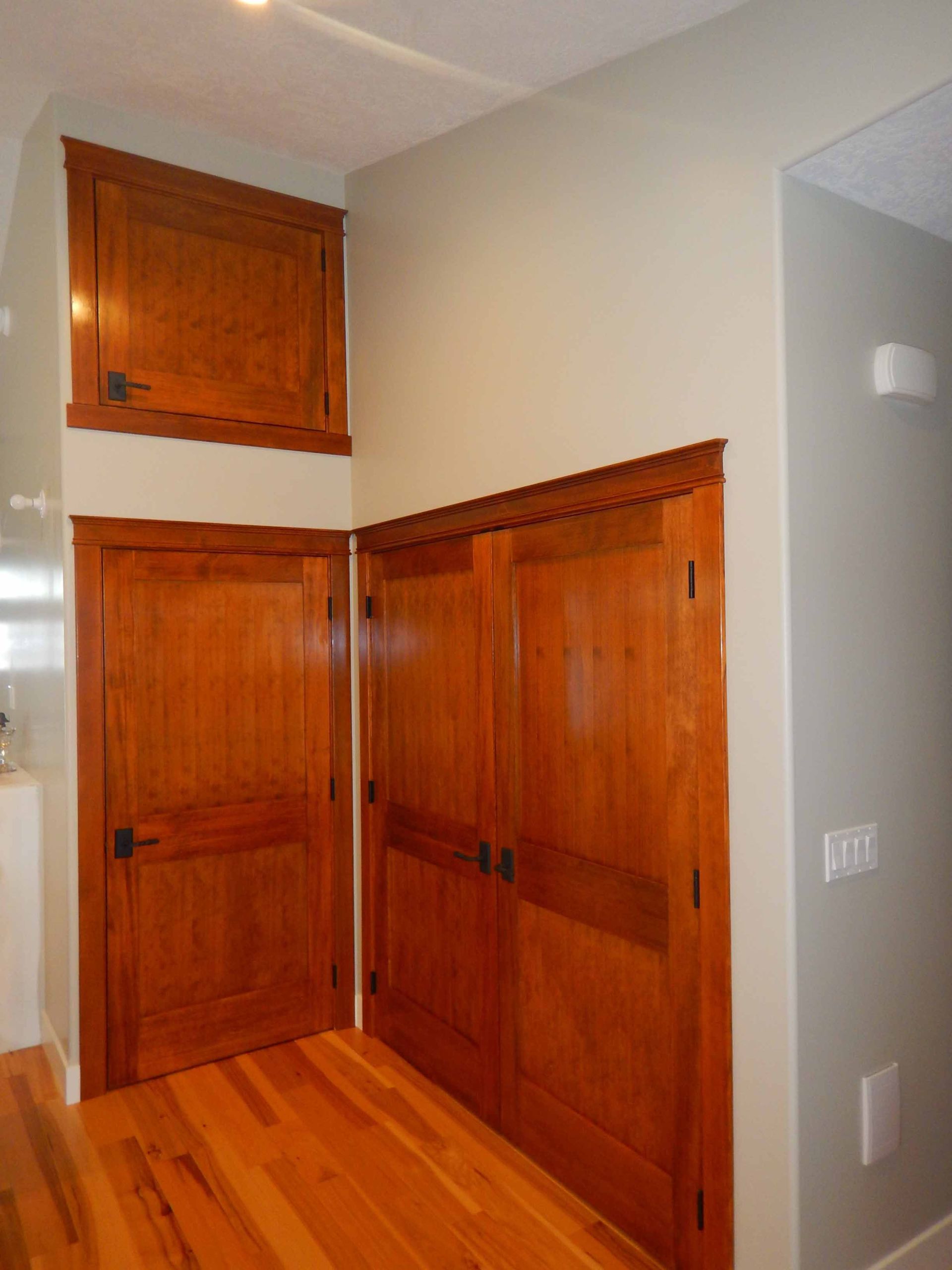 A hallway with hardwood floors and wooden doors
