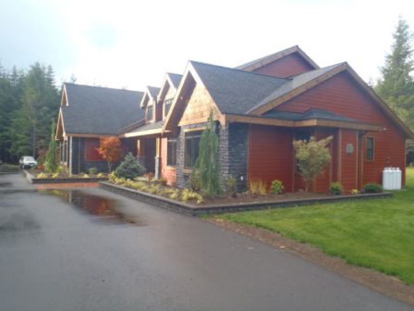 A large red house with a black roof and a white truck parked in front of it