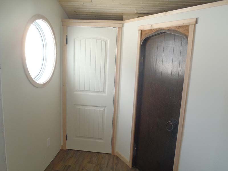 A hallway with two doors and a round window.
