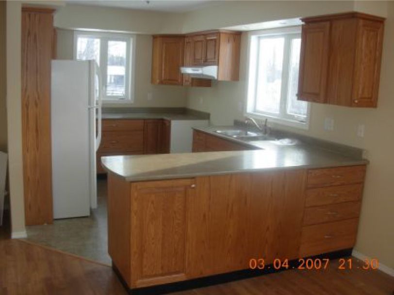 An empty kitchen with wooden cabinets and stainless steel counter tops