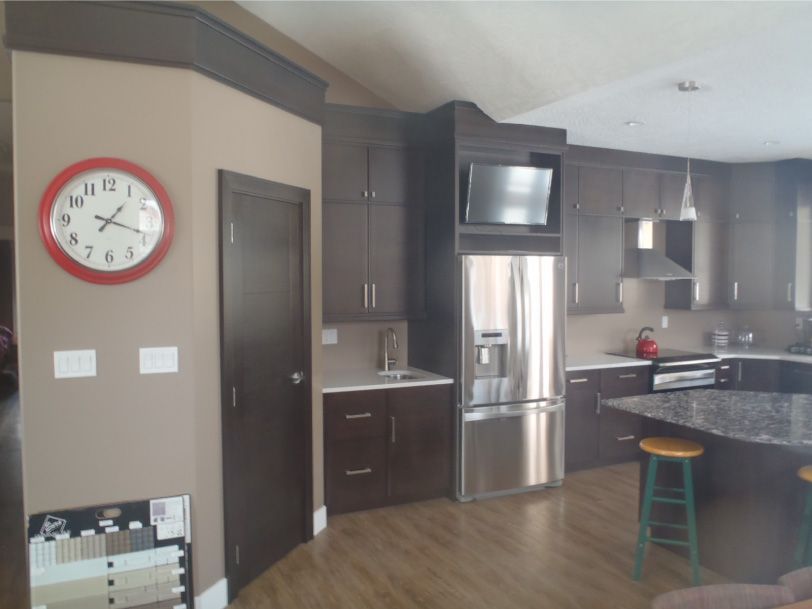 A kitchen with stainless steel appliances and a red clock on the wall
