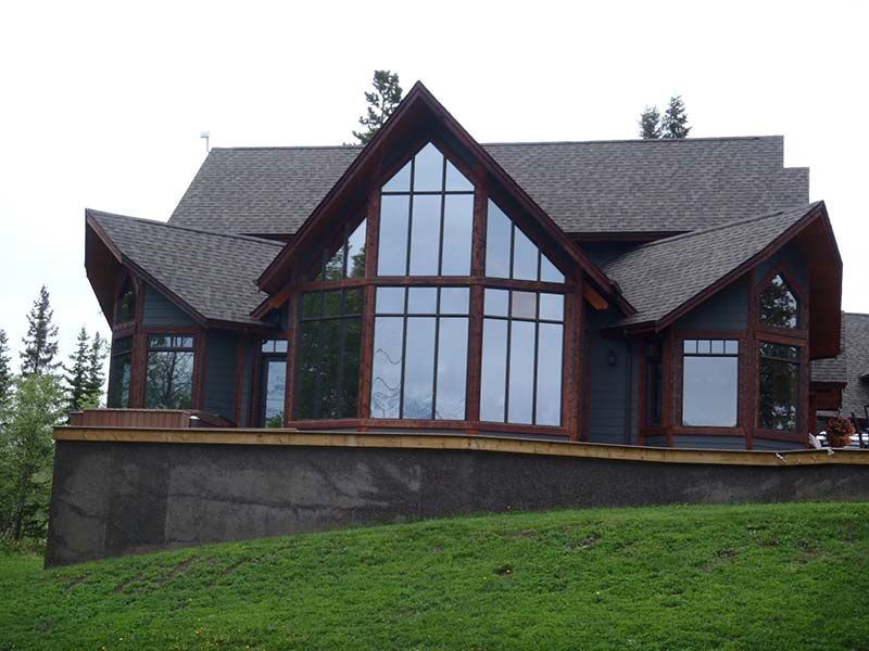 A large house with a lot of windows sits on top of a hill