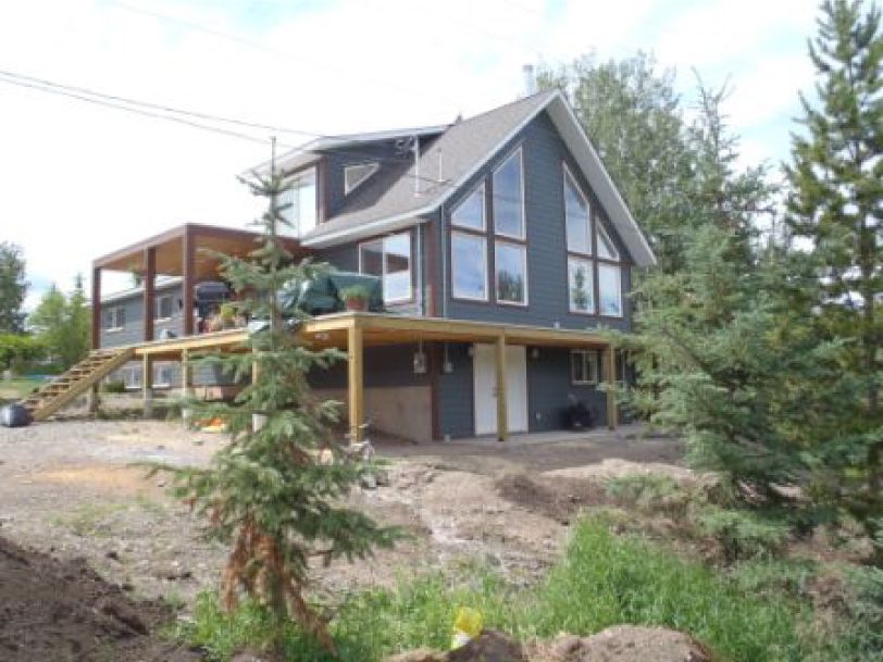 A house with a lot of windows is surrounded by trees
