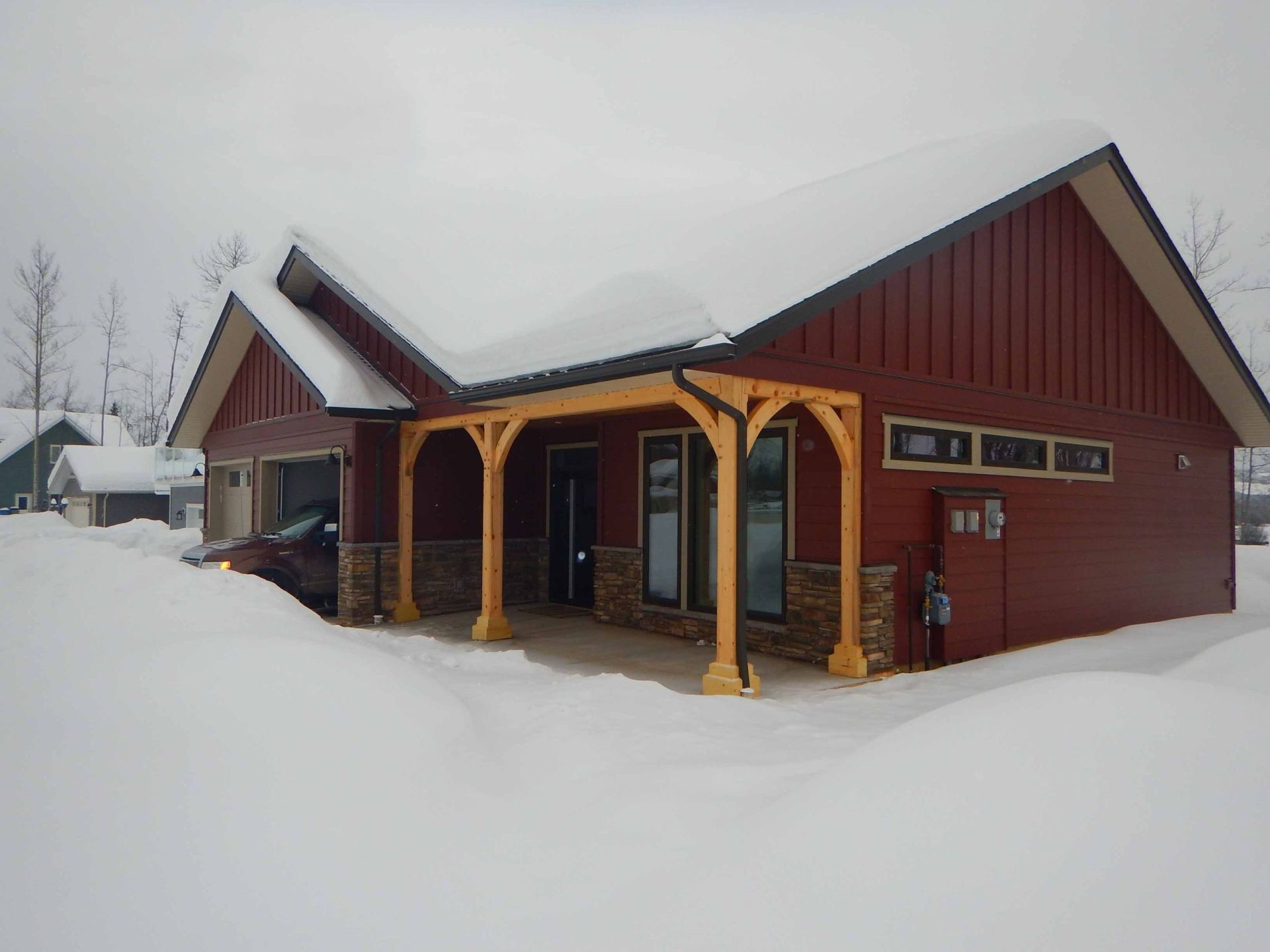 A red house with a porch is covered in snow.