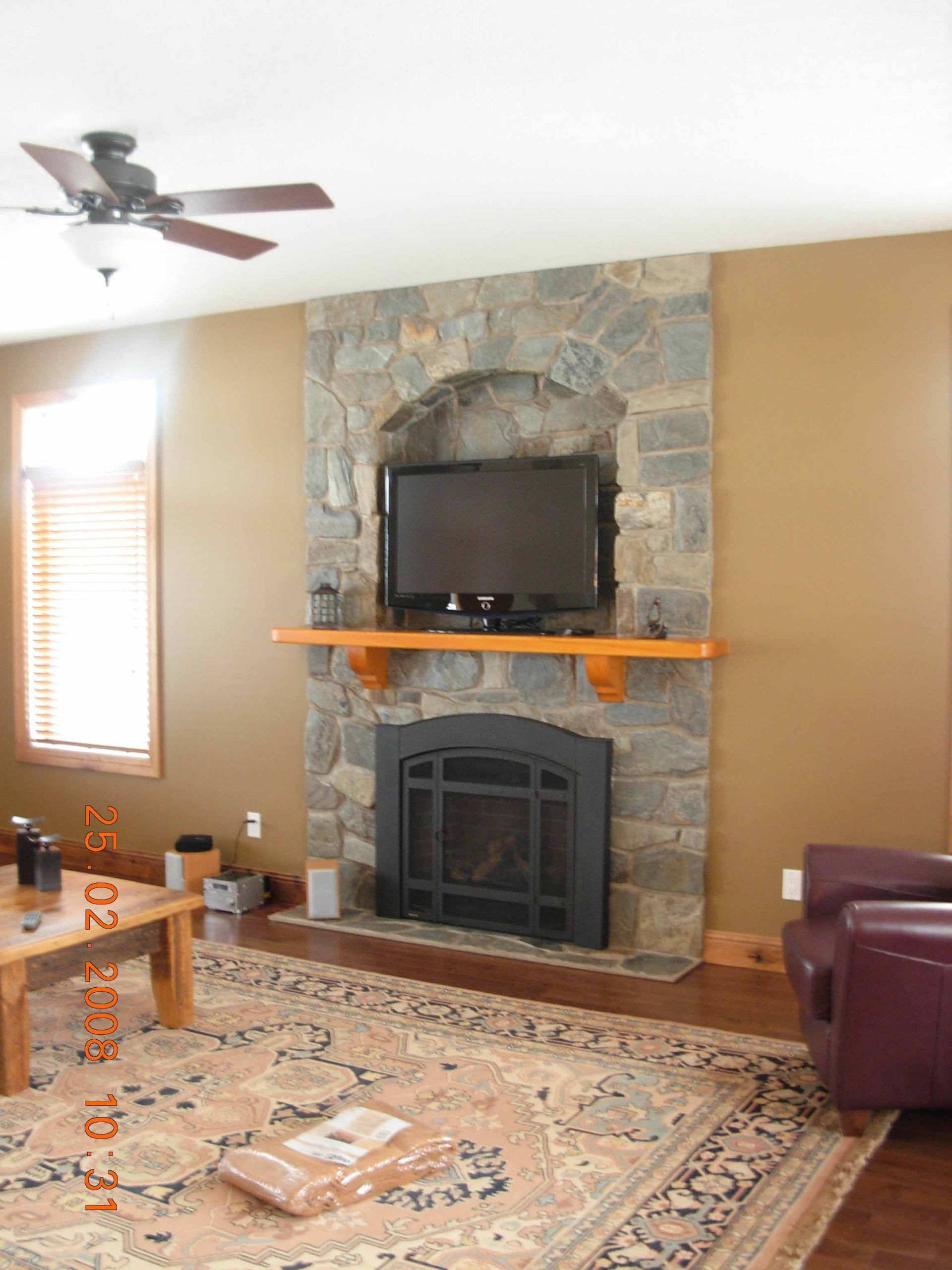 A living room with a stone fireplace and a flat screen tv