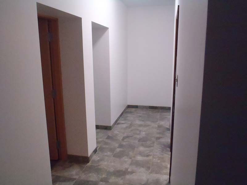 A hallway with a gray tile floor and white walls