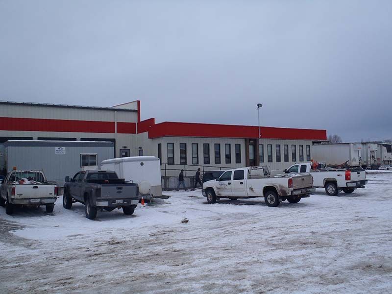 Several trucks are parked in a snowy lot in front of a building