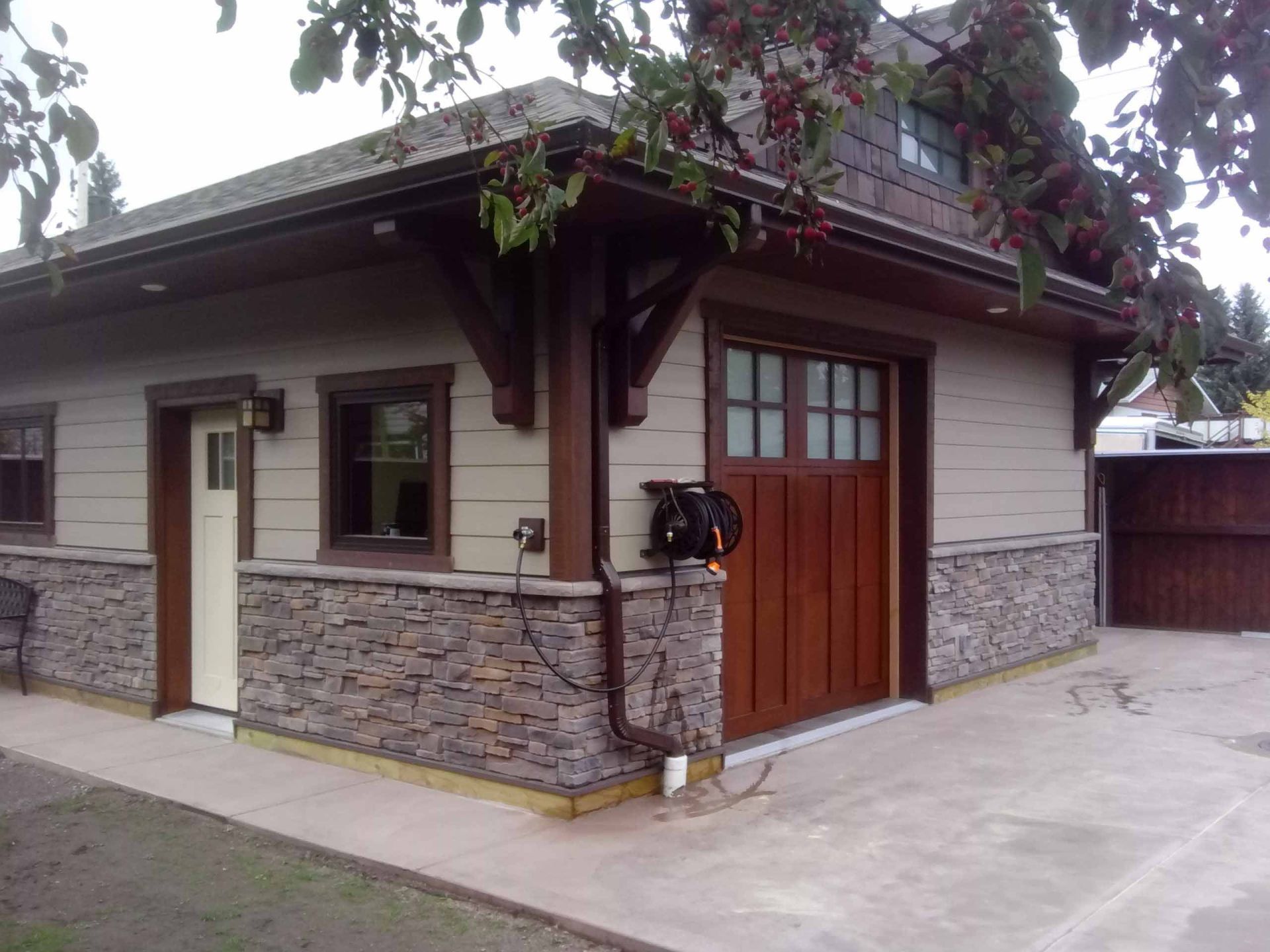 A house with a wooden garage door and a stone wall