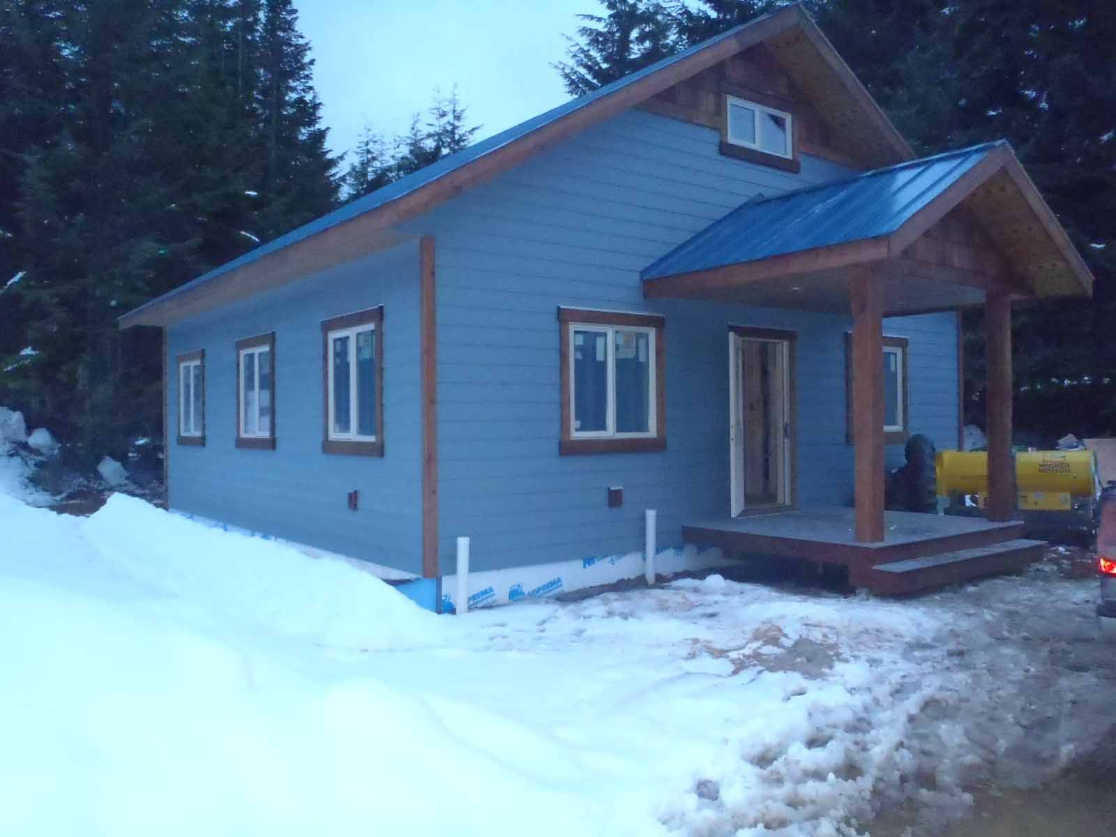 A blue house with a blue roof is surrounded by snow