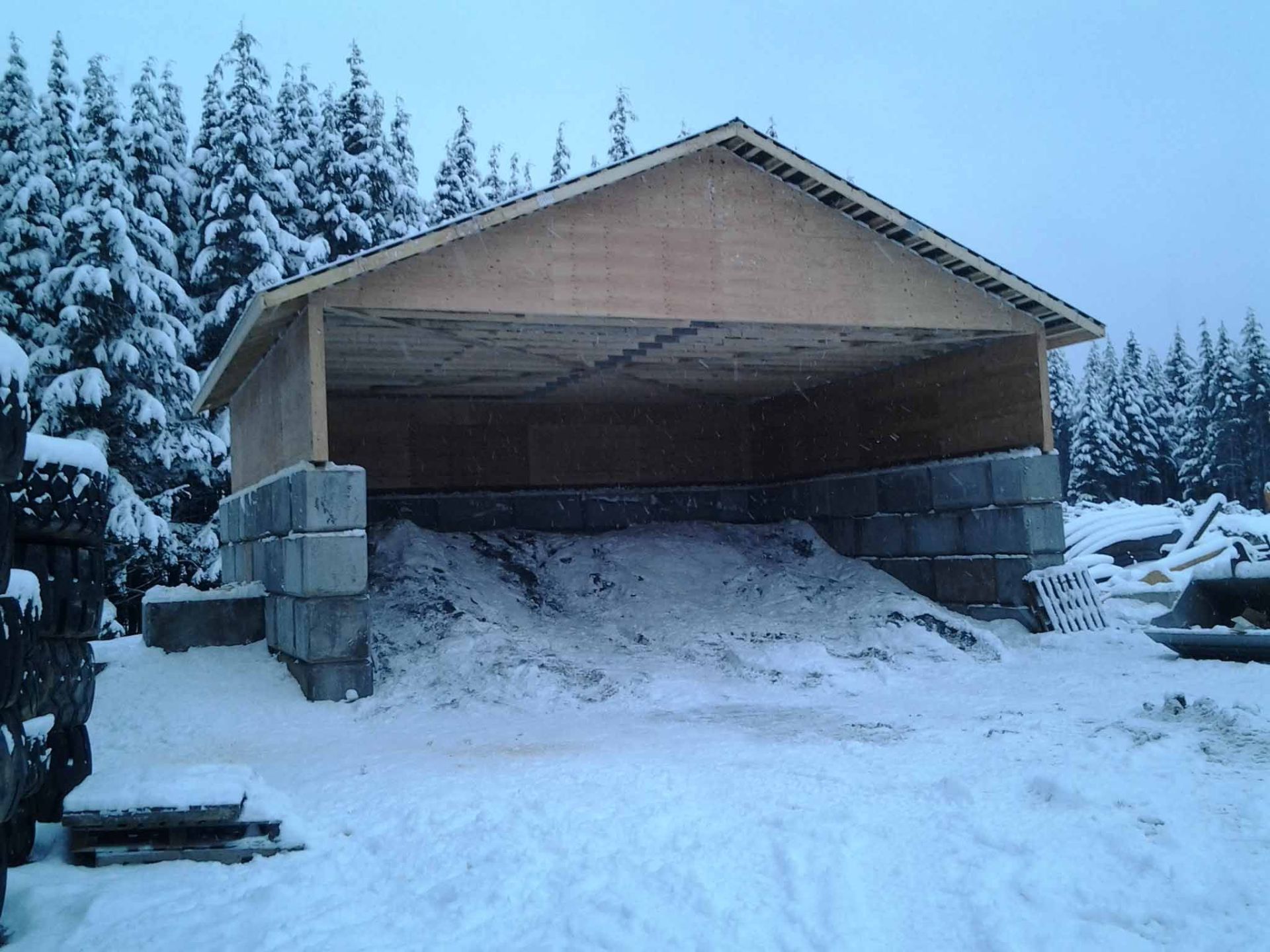 A large pile of snow is under a wooden structure