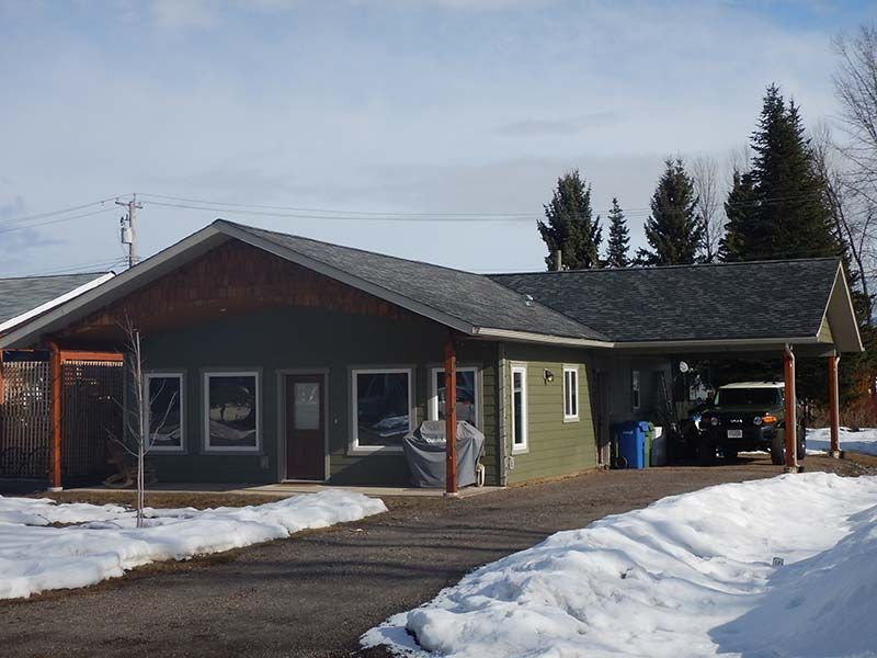 A green house with a car parked in front of it