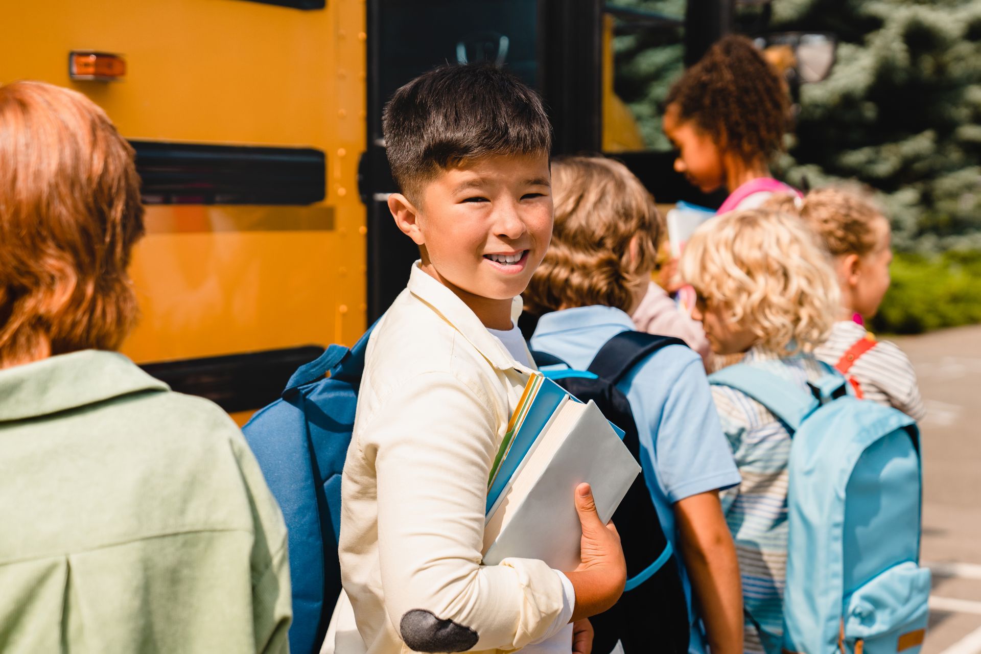 A group of children are standing in front of a school bus.