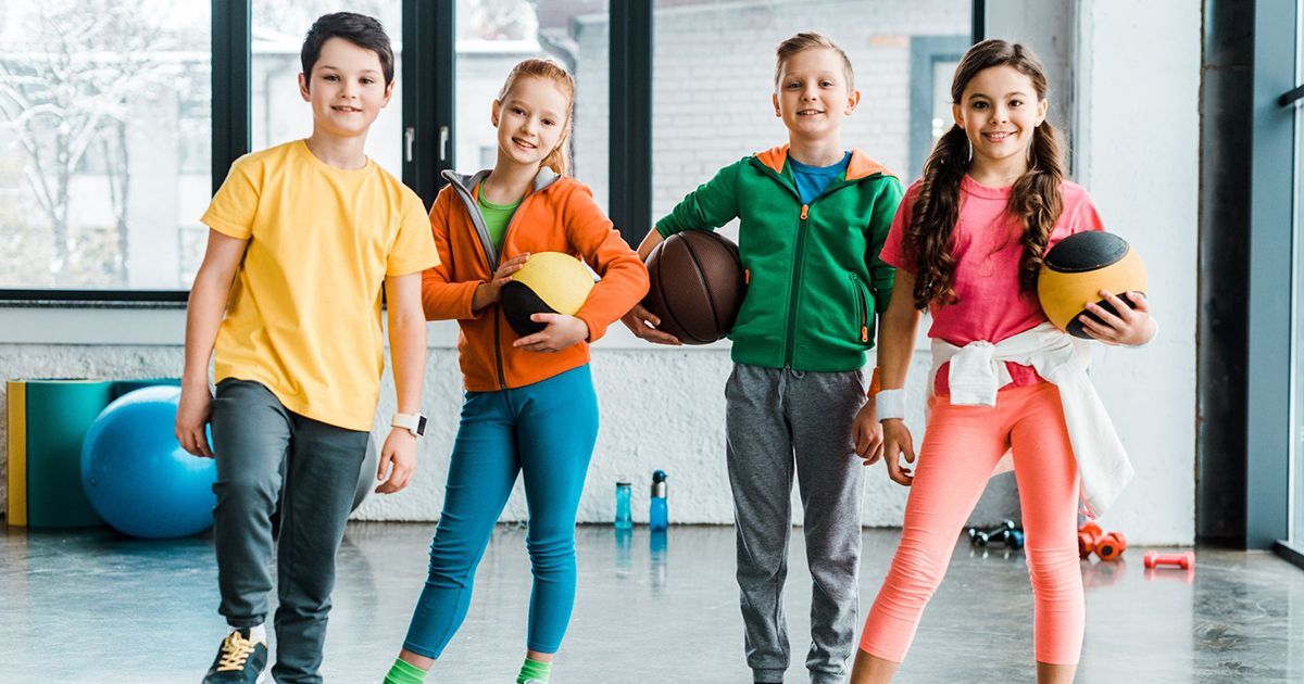 A group of children are standing next to each other in a gym holding basketballs.