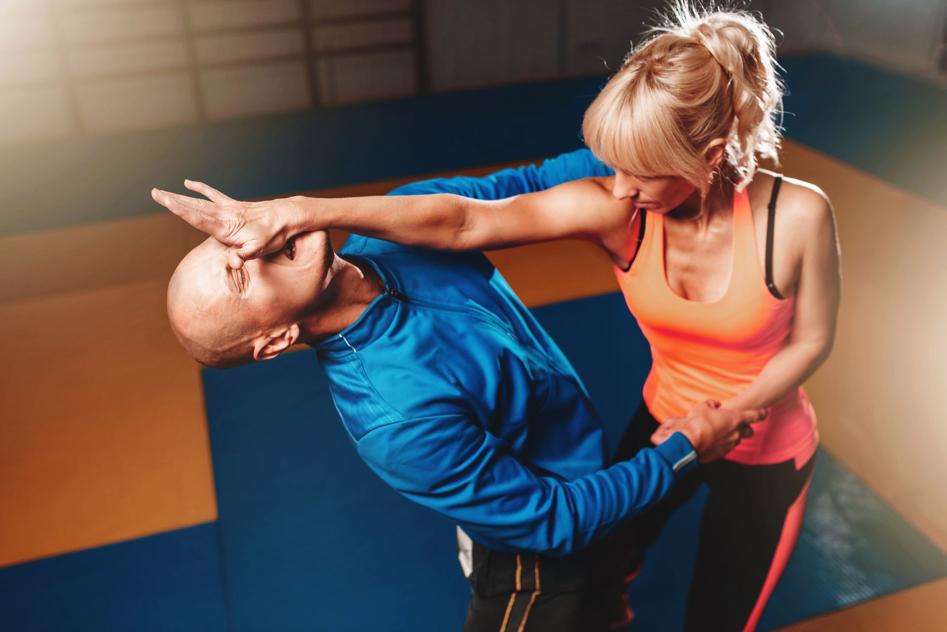 A man and a woman are practicing self defense in a gym.