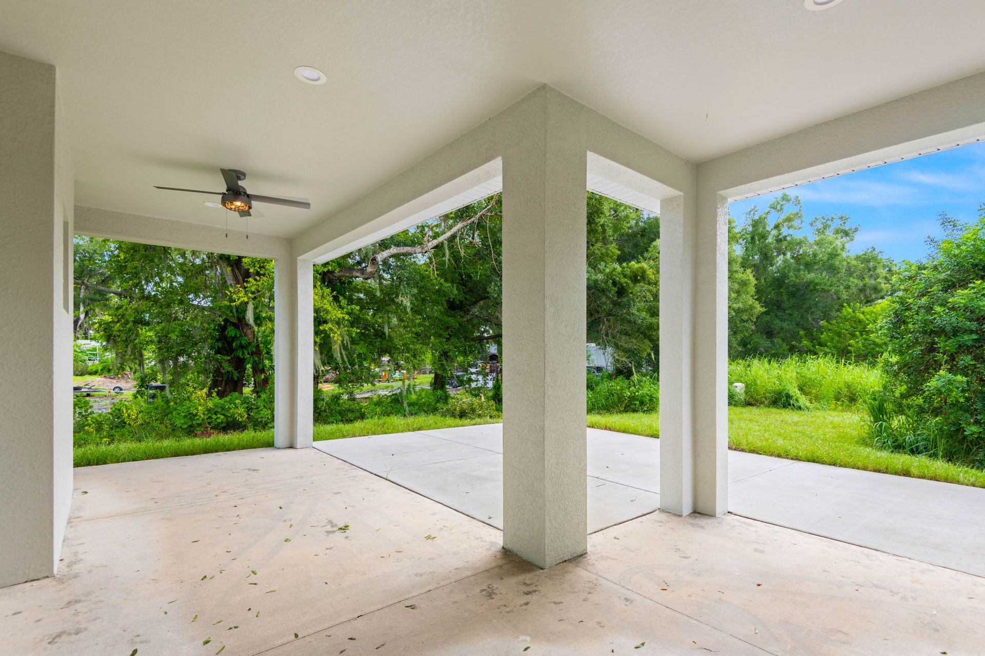 Spacious kitchen with island, pendant lights, large windows overlooking a backyard and a fireplace on a black wall.