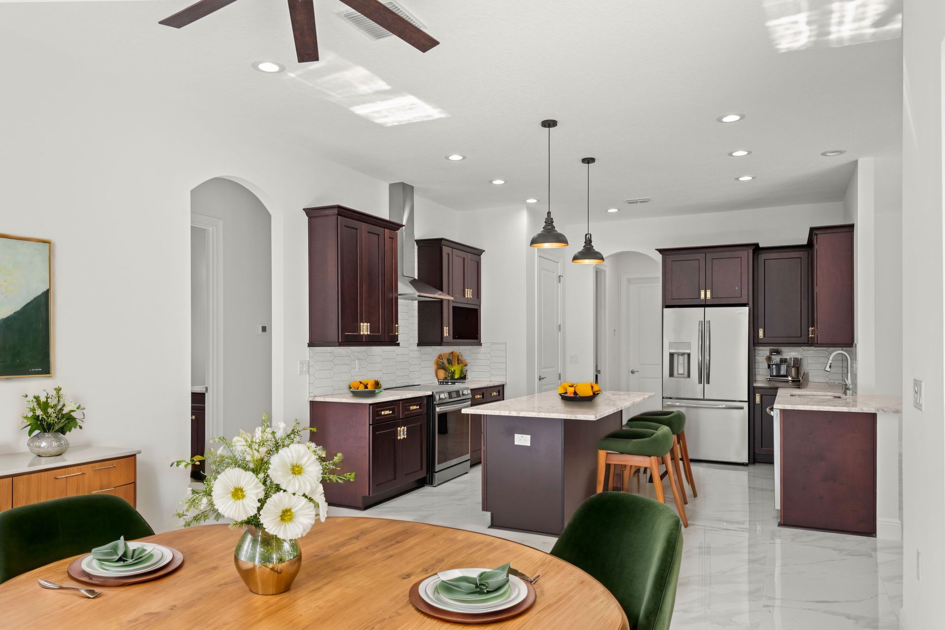 Modern kitchen with dark wood cabinets, a central island, stainless steel appliances, and an adjacent dining area.
