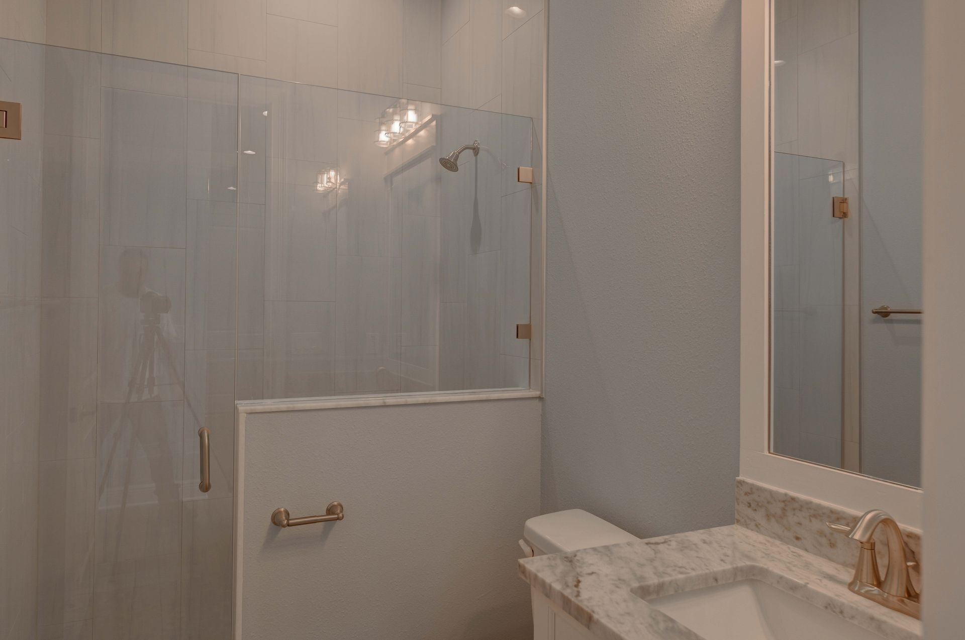 Spacious kitchen with island, pendant lights, large windows overlooking a backyard and a fireplace on a black wall.