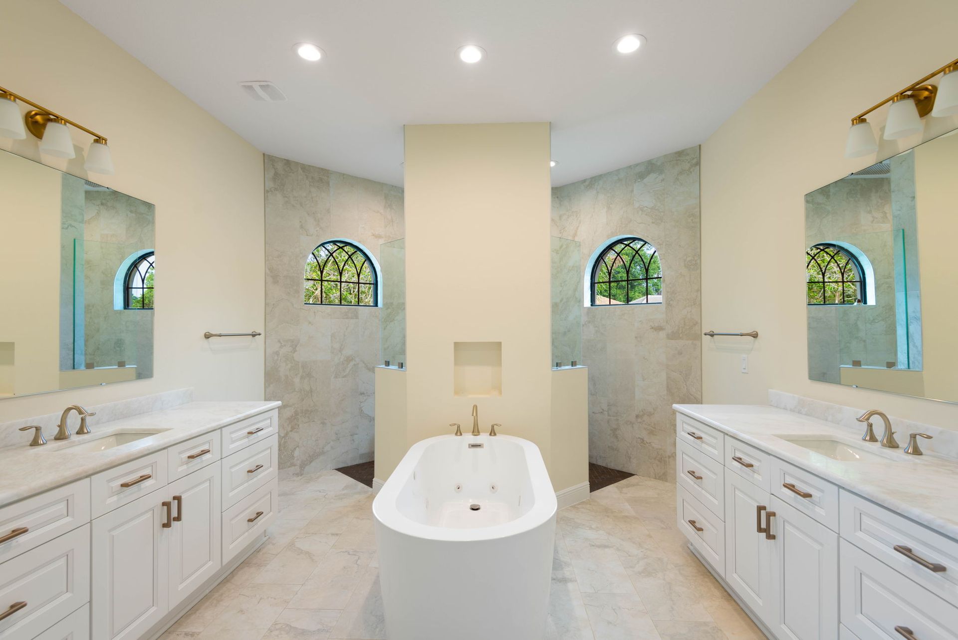 Spacious, modern bathroom with white fixtures, two showers, and a central tub. Neutral tones, natural light.
