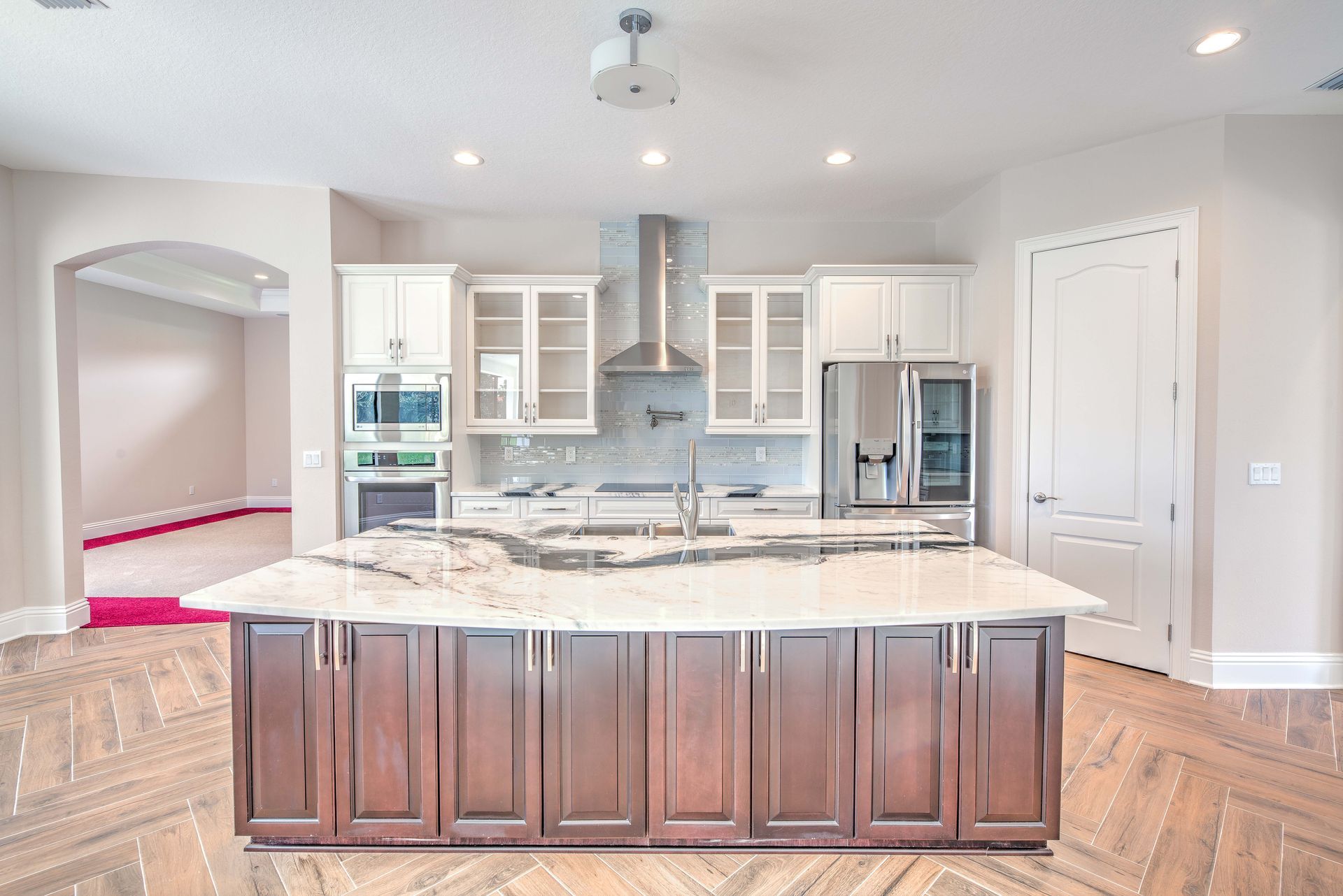Modern kitchen with large island, white cabinets, and stainless steel appliances.